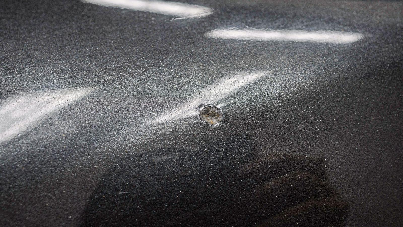 Macro view of clearcoat with paint depth and film edge readings pinned to the surface